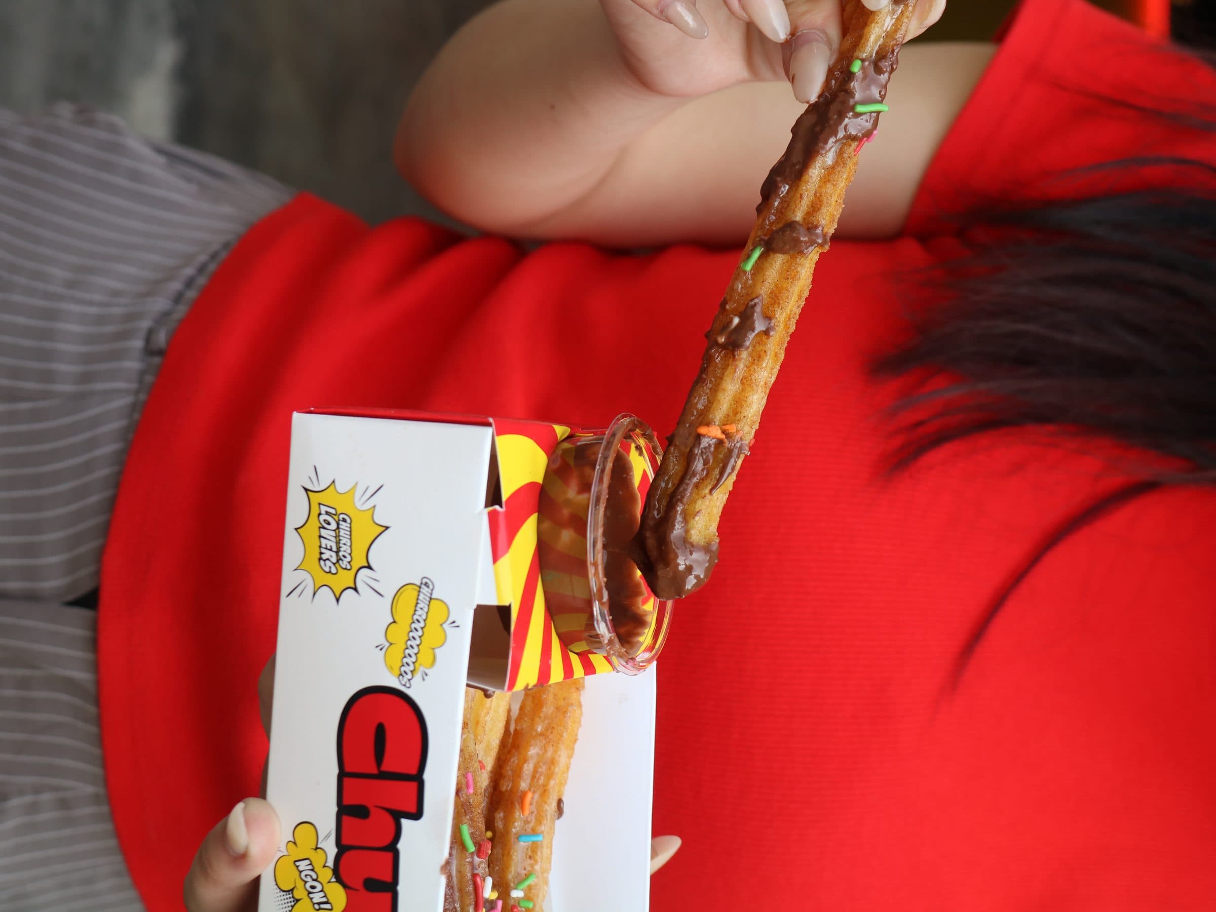 Churro being dipped into chocolate sauce