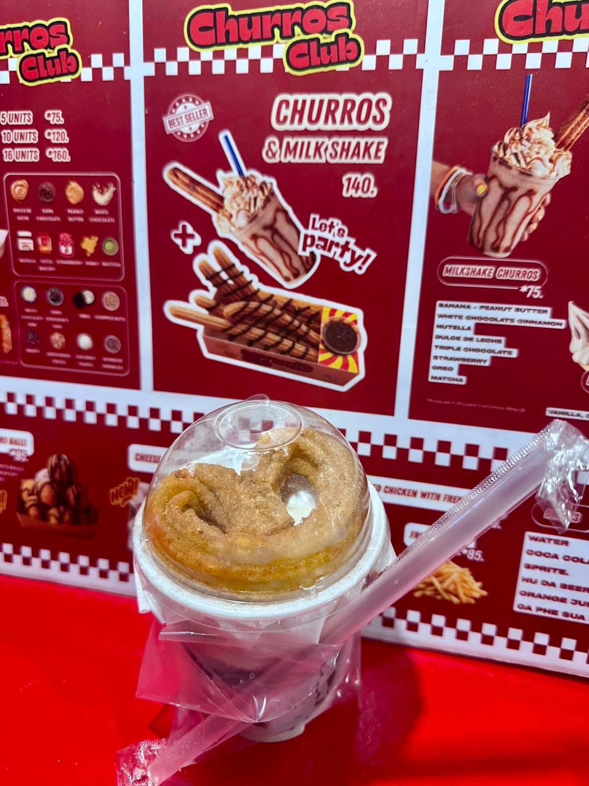 Churro cup in front of the Churros Club menu board