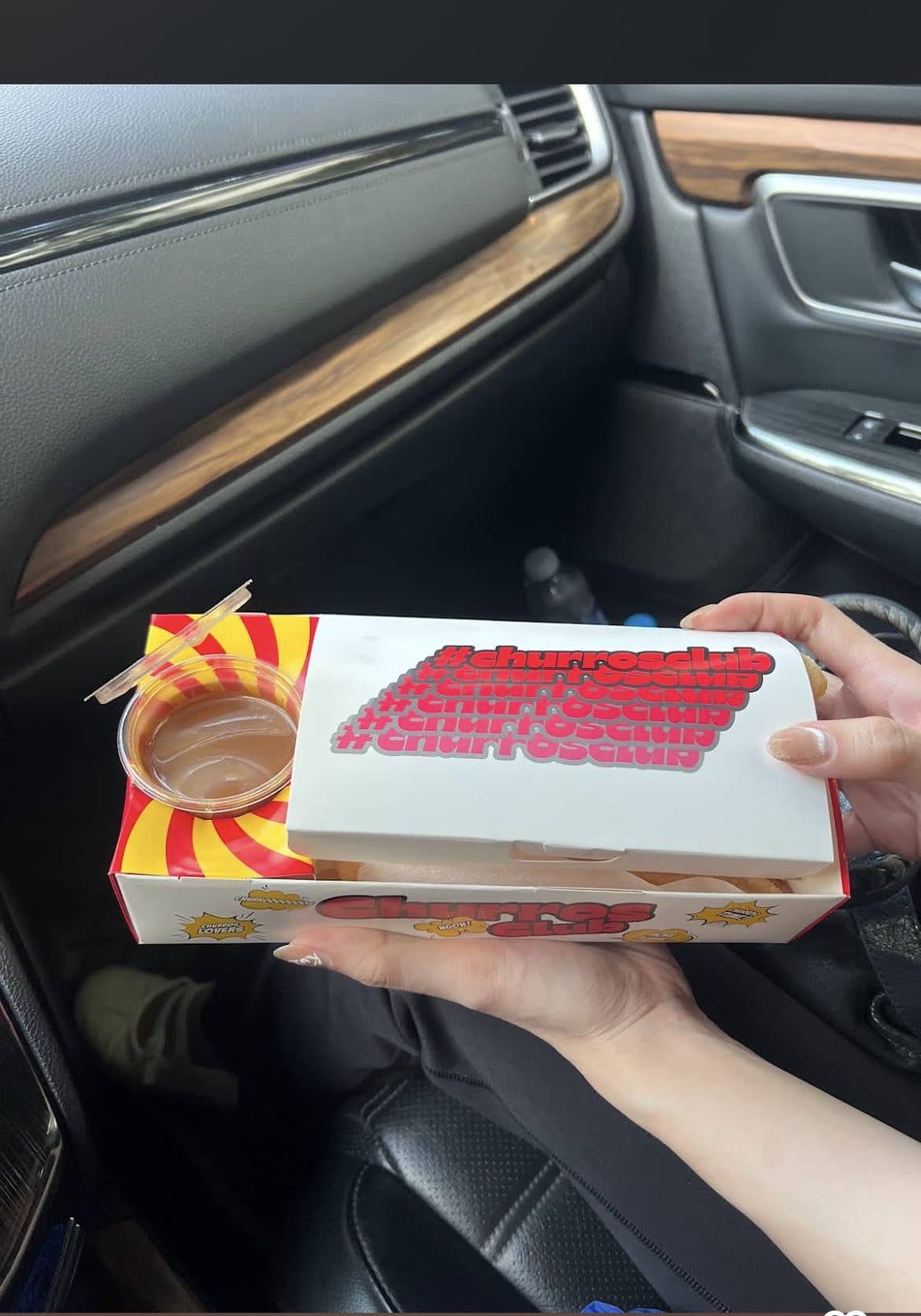 Box of churros held up in a car, ready for the road