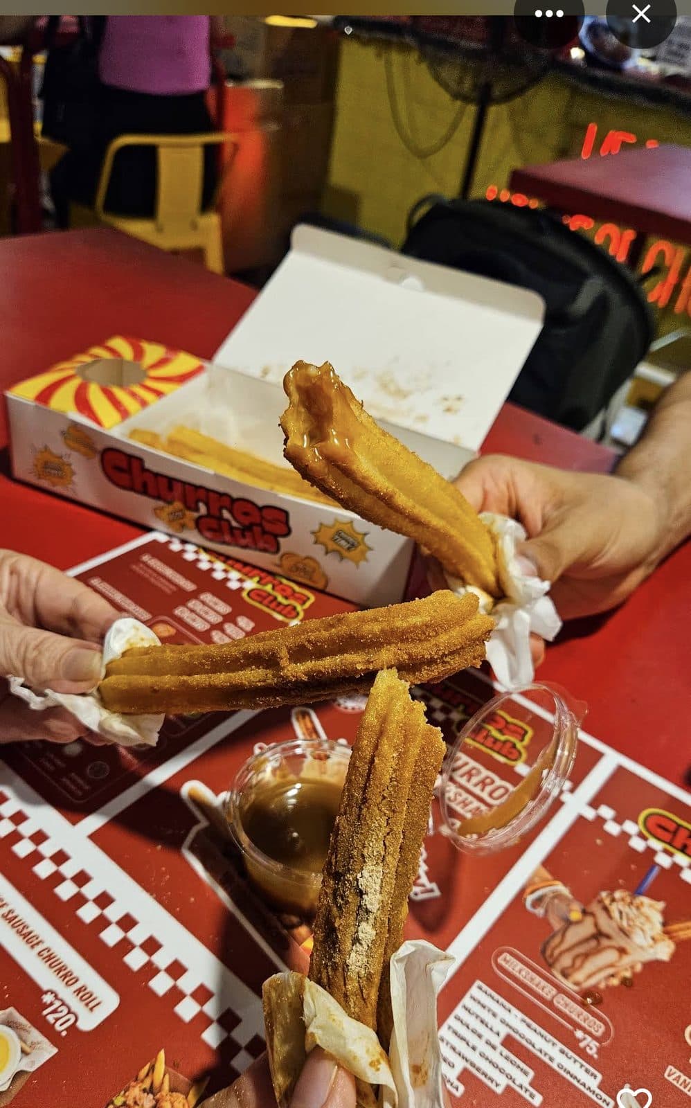 Friends splitting fresh churros at the table
