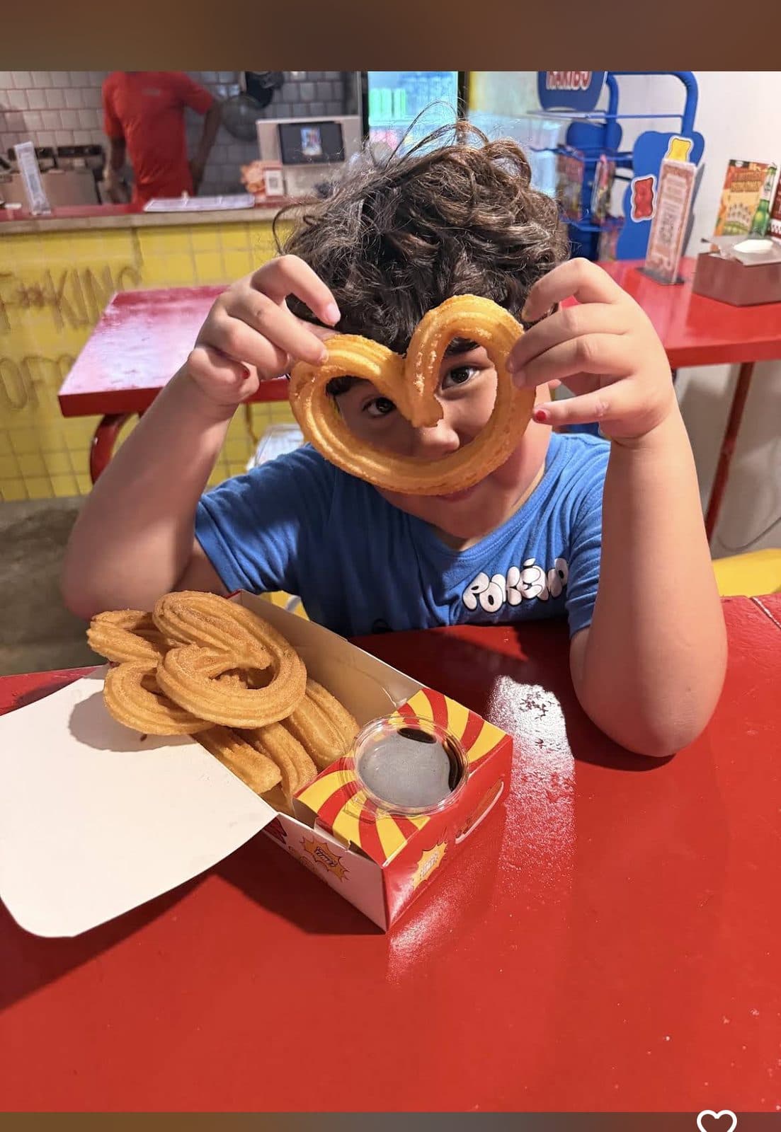 Kid making a heart shape with a churro
