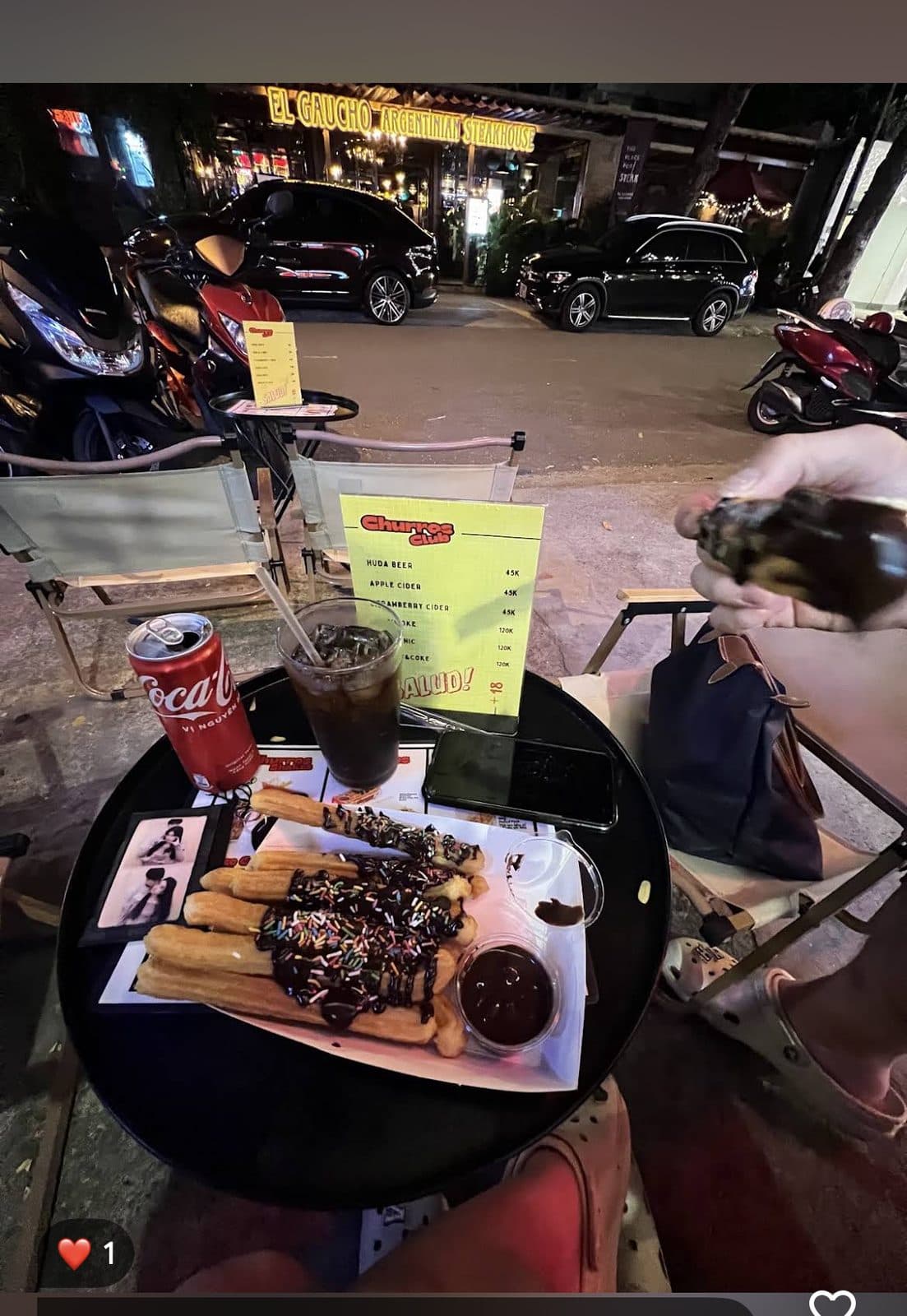 Chocolate-drizzled churros with sprinkles on a streetside table